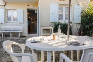 a white table with chairs and a bottle on it at Location Oléron, proche plage in Dolus-d'Oléron +12 photos