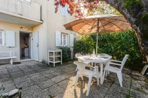 a table and chairs with an umbrella on a patio at Location Oléron, proche plage in Dolus-d'Oléron