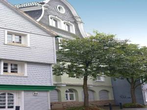 a large house with a clock tower and a tree at Serviced Apartments Xanthurus in Schwelm