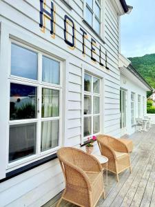 a white house with wicker chairs and a sign on it at Tørvis Hotell in Luster
