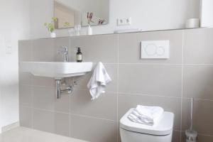 a white bathroom with a sink and a toilet at Kajüte in Böhl