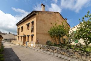 a building with a stone wall next to a street at La Casa de Dafne Almendro in Santo Tomé del Puerto