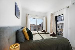 a bedroom with a bed and a large window at Casinha in Burgau