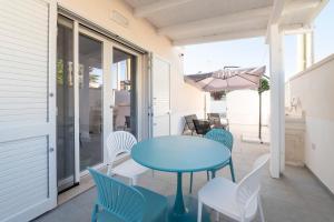 a blue table and chairs on a porch with an umbrella at Briamar Residence in Torre dell'Orso