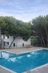 a blue swimming pool in front of a white building at Sol Isla - Binimar in Arenal d'en Castell
