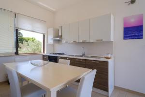 a kitchen with a white table and a table and a window at Villa Scoglio in Melendugno