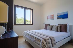 a white bedroom with a bed and a window at Villa Scoglio in Melendugno