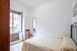 a white bedroom with a bed and a window at Valle Inclan in Villanueva de Arosa
