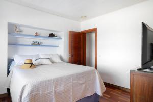 a bedroom with a white bed and a television at El Mar y Tú in Arrieta