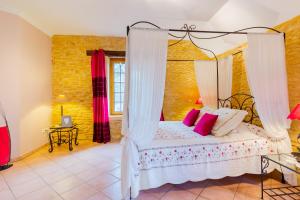 a bedroom with a canopy bed with pink pillows at La Noyeraie - Chambre d'hotes in Saint-Amand-de-Coly