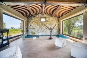 a large room with large windows and a stone wall at Le Buccole Country House in Marsciano