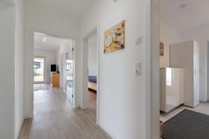 a living room with white walls and wooden floors at Seelenwärmerstuuv in Kronprinzenkoog