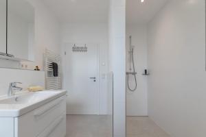 a white bathroom with a shower and a sink at Seelenwärmerstuuv in Kronprinzenkoog