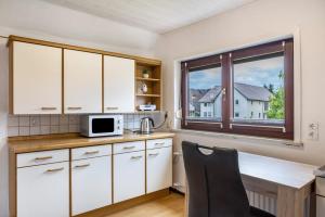 a kitchen with white cabinets and a table and a window at Ferienwohnung Hennen in Witzenhausen