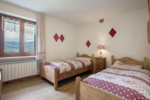 two beds in a bedroom with a window at Appartamento Pila Vacanze in Gressan