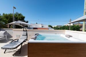 a hot tub on a patio with a chair and an umbrella at Briamar Residence in Torre dell'Orso
