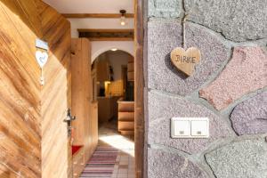 a wooden heart on a stone wall next to a door at Thomasegg Hof Birke in Sarntal
