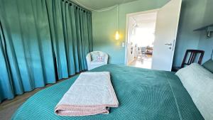 a bedroom with a green bed with a towel on it at Bayerwaldresort in Sankt Englmar +27 photos