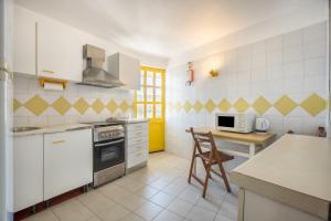 a kitchen with white appliances and a yellow door at Apartamento Amarelo T1 in Odeceixe +12 photos