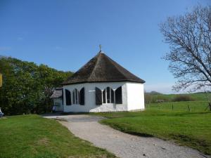 a small white church with a black roof at Ferienwohnung Hiddenseeblick 2 in Dranske