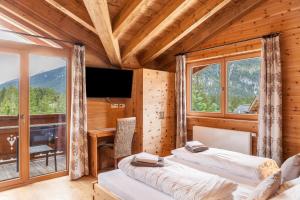 two beds in a room with a desk and a television at Mountainlodge in Leutasch
