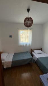 two beds in a bedroom with a window and a chandelier at Laura Apartment in Tribunj