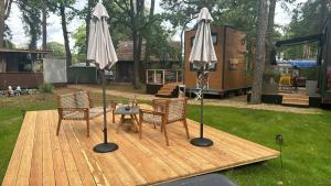 a wooden deck with two umbrellas and a table and chairs at Tiny House Nr 2 in Schwielowsee +8 photos