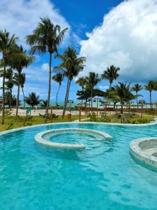 a swimming pool with palm trees in the background at Casa Verde Mar Naluum in Passo de Camarajibe +89 photos