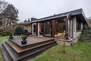 a house with a wooden deck in the yard at Ferienhaus Timm in Meldorf