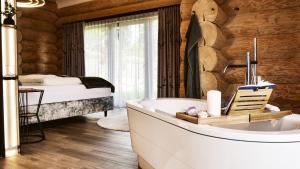 a bathroom with a tub and a bed in a room at Naturstamm Chalets in Untergriesbach