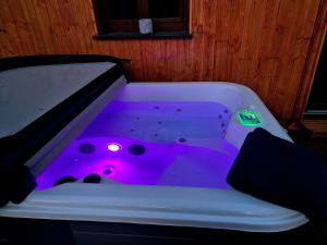 a bathtub with purple lighting in a room at Le Chalet Cocon et Jacuzzi in La Petite-Pierre