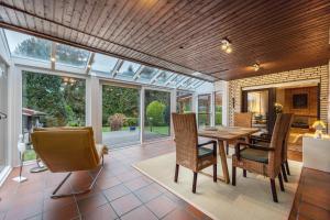 a conservatory with a dining room with a table and chairs at Ferienhaus Timm in Meldorf