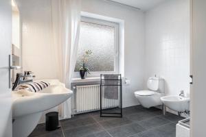 a white bathroom with two sinks and a toilet at Ferienhaus Auszeit Meer in Cuxhaven +23 photos