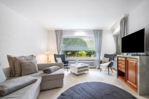 a living room with a couch and a flat screen tv at Ferienhaus Auszeit Meer in Cuxhaven