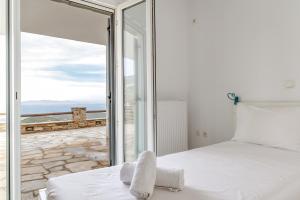 a bedroom with a bed and a large glass window at Vassilis Family Villa Tinos in Triandáros