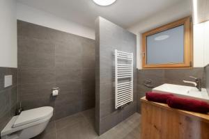a bathroom with a toilet and a sink and a window at Tholerhof in Schenna +56 photos