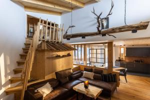 a living room with a leather couch and a staircase at See das Ferienhaus in Oetz