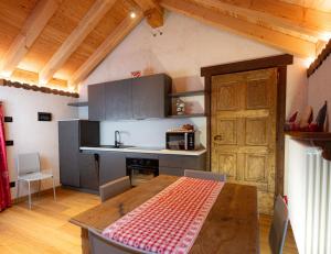 a kitchen with a wooden table and a wooden door at Casa Girod - Rascard in Issime +11 photos
