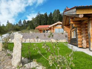 a log cabin with a stone fence and a house at Naturstamm Chalets in Untergriesbach