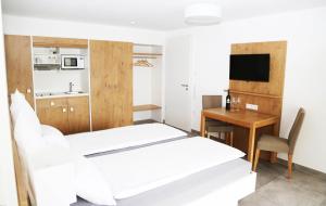 a room with two beds and a desk and a kitchen at Ferienwohnungen Joachim Fischer in Gündelbach