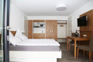 a bedroom with a bed and a desk and a kitchen at Ferienwohnungen Joachim Fischer in Gündelbach