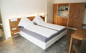a bedroom with a bed with white sheets and pillows at Ferienwohnungen Joachim Fischer in Gündelbach