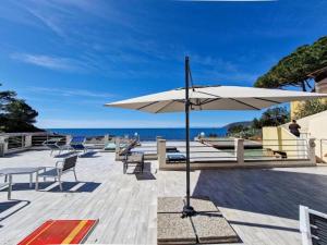 a patio with chairs and an umbrella and the ocean at Villa Galatea Exclusive in Capoliveri