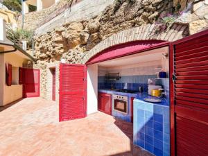 a kitchen with red doors and a stone wall at Villa Galatea Exclusive in Capoliveri