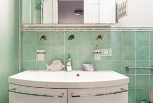 a bathroom with a white sink and green tiles at Villa Galatea Exclusive in Capoliveri
