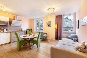 a kitchen and living room with a table and green chairs at Serviced Apartments Xanthurus in Schwelm