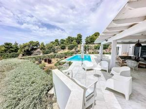 a patio with white chairs and a swimming pool at The Privacy Villa by Seaviews in Porto Heli