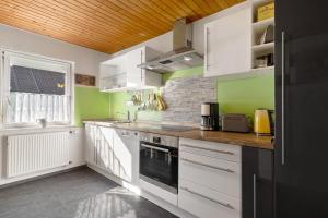 a kitchen with white cabinets and green walls at Haus Kornfeld in Kehl am Rhein