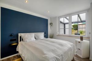 a bedroom with a white bed and a blue wall at Ferienbungalow Süssau in Süssau