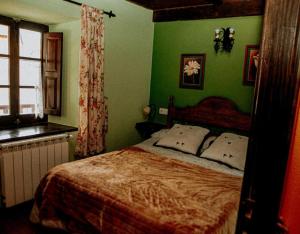 a bedroom with a bed with green walls and a window at El Jermoso in Posada de Valdeón
